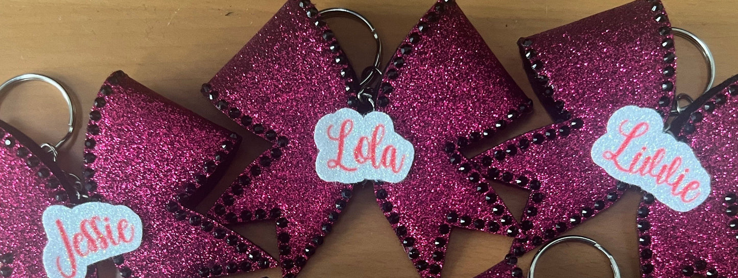 Pink glittery bows with names on a wooden surface