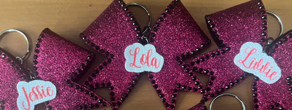 Pink glittery bows with names on a wooden surface
